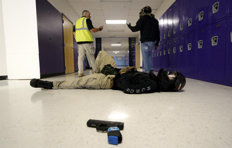 Joe Deedon (L,) president of TAC ONE Consulting, debriefs a student after a scenario with a mock victim (foreground) in a middle school during an Active Shooter Response course offered by TAC ONE in Denver April 2, 2016. REUTERS/Rick Wilking