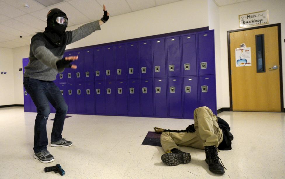 A student (L) responds to commands from a simulated law enforcement training, with a mock victim on the floor in a middle school, during an Active Shooter Response course offered by TAC ONE Consulting in Denver April 2, 2016. REUTERS/Rick Wilking